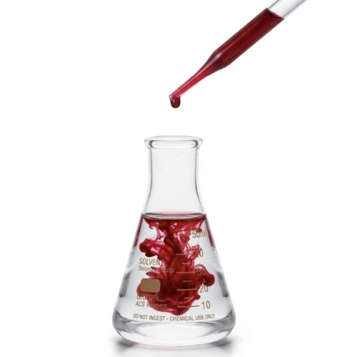 A pipette adding a single drop of concentrated red natural colors colorant into an Erlenmeyer flask filled with water, showing the dispersion process. This represents the high-purity formulation of BioconColors natural colorants.